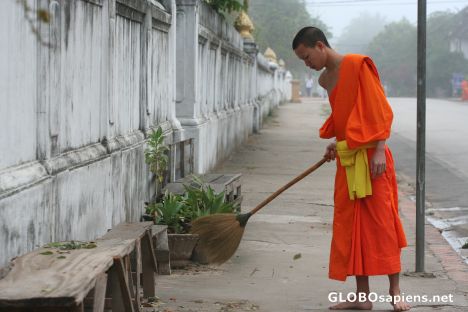 A monk tiding up the street after gathering food