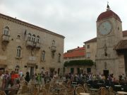 The John Paul II Square with the clock tower and the tables of the open-air cafes.