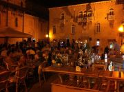 The John Paul II Square at night with the Corte's bar and tables.