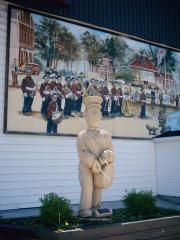A wooden Truro monument with a mural in background